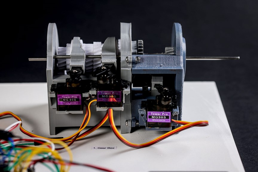 Grey system with gears, servo motors and coloured wiring attached.