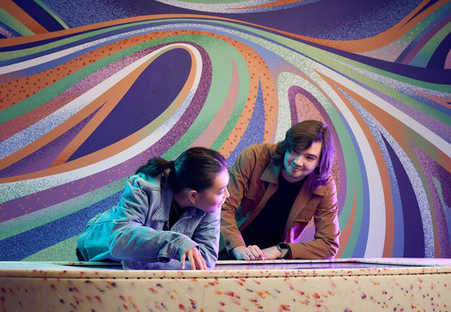 Two people use an interactive display inside Our Wonderous Planet exhibition at Melbourne Museum.