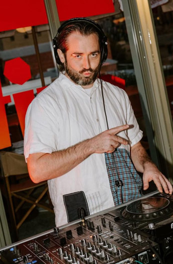 Danny with a beard and white shirt scratching on a dj deck.