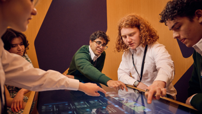 A group of students use a touch table to edit a video ad.