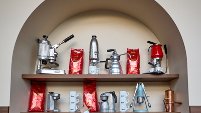 A Brunetti Classico waiter reaches for coffee grounds from a shelf.