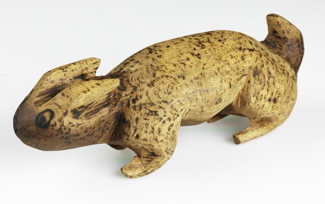 Small carved wooden animal figure with speckled surface.