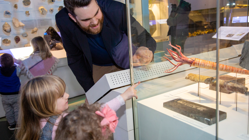 A Programs Officer shows children displays in the 600 Million Years exhibition.