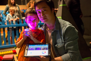 A parent and child hold an ipad showing the on-screen controls used to control sphero robts.