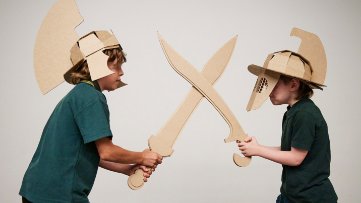 Two children dressed up with cardboard helmets and swords
