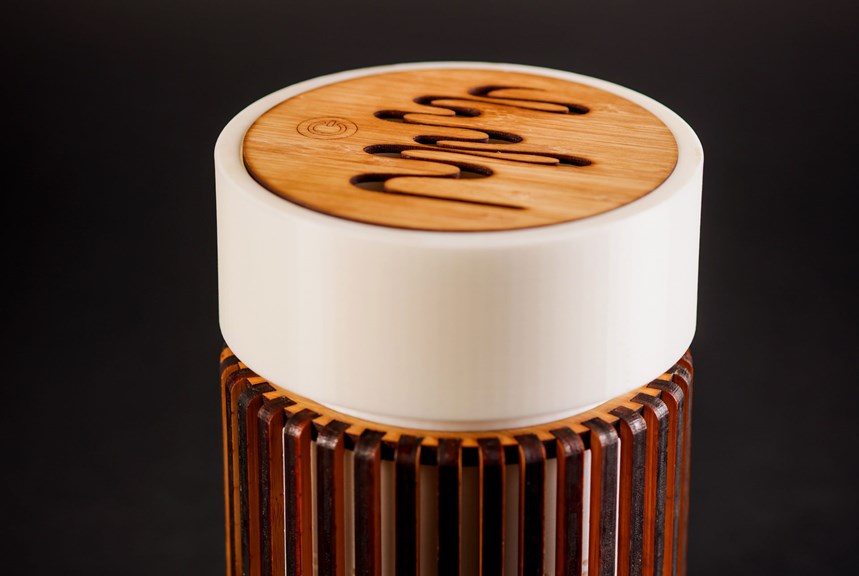 Bamboo air purifying unit with carved design and a power switch on top.