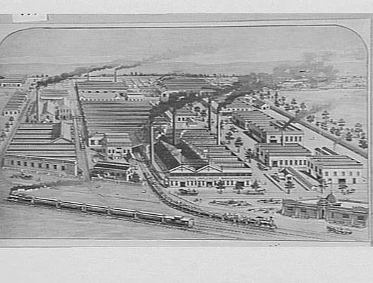Aerial view of a large factory complex and surrounds. Including a train in the foreground