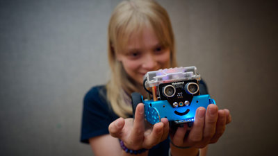 A young adult holds a robot up to the camera from Robots and coding workshop at Scienceworks.