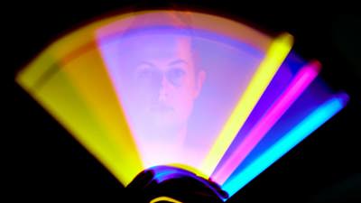 Person waving a light source in each hand to create a circle-shaped light pattern in a variety of colours.