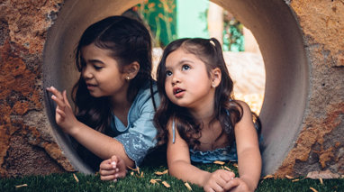 Two girls inside a rock tunnel outside