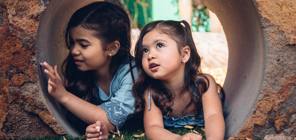 Two girls inside a rock tunnel outside