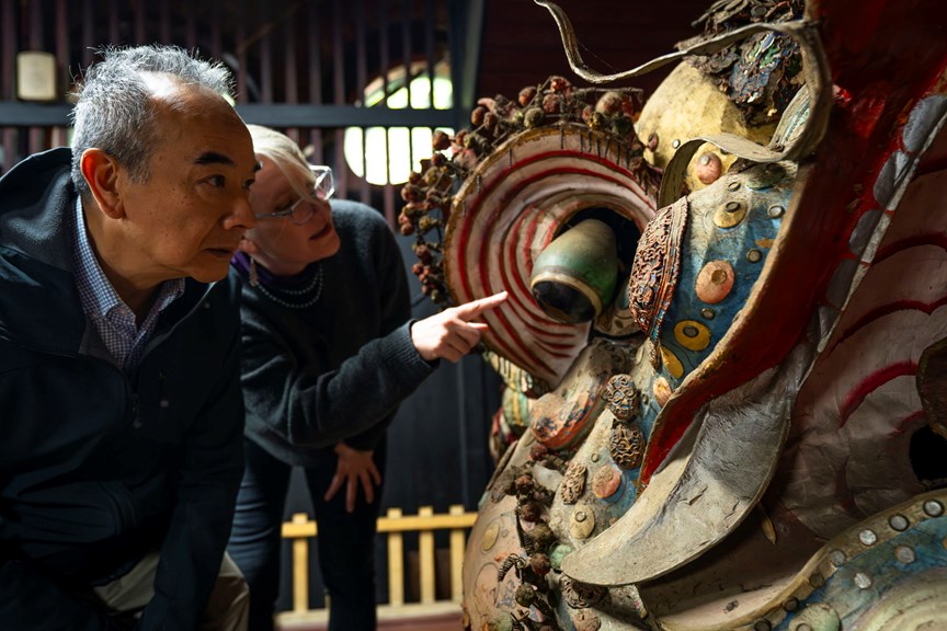 a man and a woman looking over a colourful Chinese dragon head