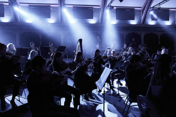 An orchestra playing under blue spotlights.
