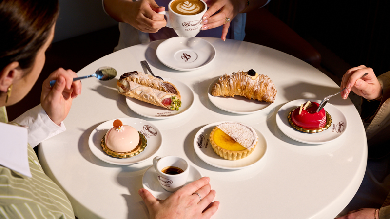 Thee people enjoying assorted Brunetti Classico deserts and coffee.