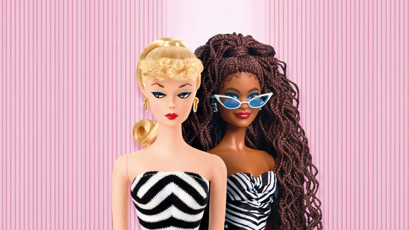 Two barbie, one looking judgmental  in a black and white stripe shoulderless dress, and the other smiling at the camera in a similar dress.