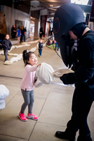 A small child hands a bread crumb replica to one of the worker ants.