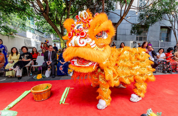 Performers doing a lion dance in a bright orange chinese lion costume
