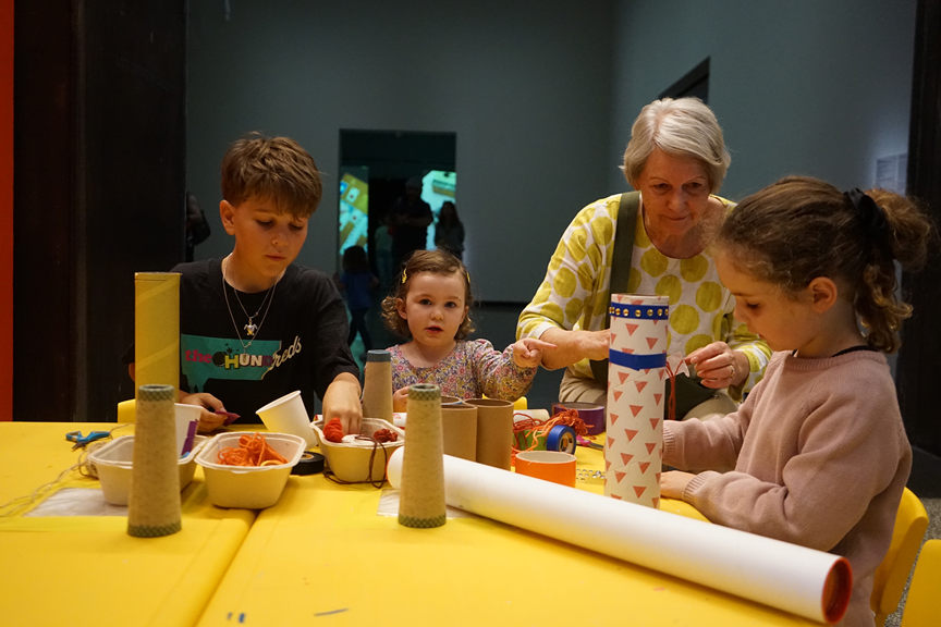Three children and their guardian at crafting during a family art day.