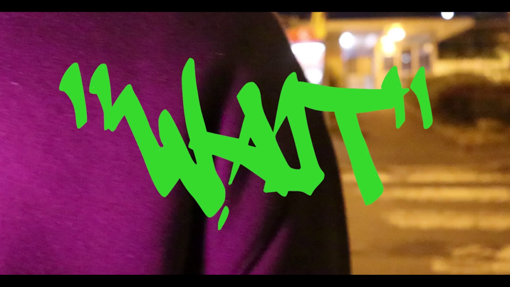 The word 'WAIT' in lime-green graffiti-style writing, overlaid on a close-up of purple fabric, with a blurred, nighttime urban background.