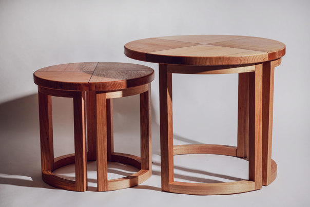 A pair of wooden nesting tables with segmented, circular tops and curved legs in contrasting light and dark timber tones.