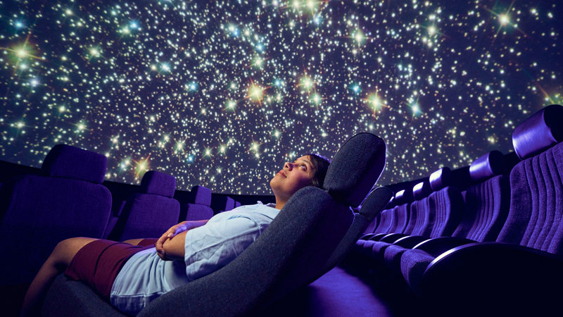 A primary school student observes a projection of a spiral galaxy on the dome of the Melbourne Planetarium.