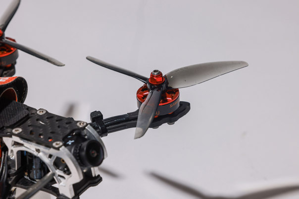 Close-up photo of a transparent black drone propeller with red-metal fixtures.