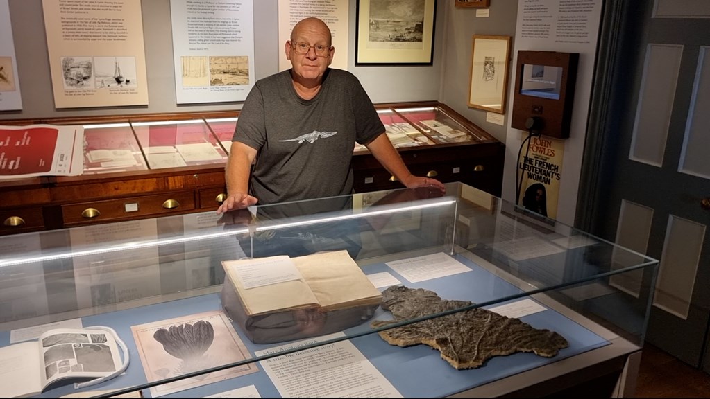 A man standing in front of a glass case filled with books