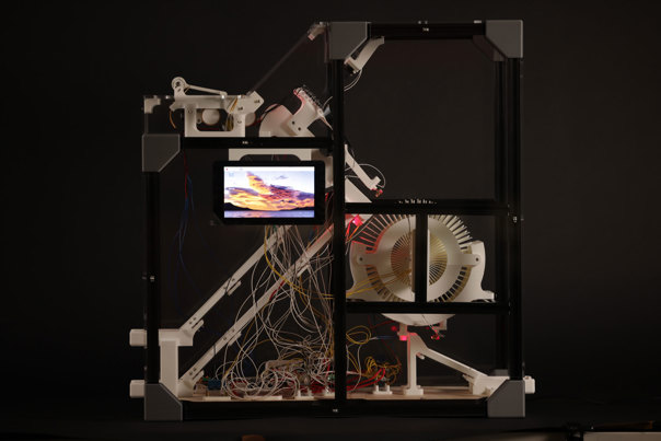 Transparent acrylic cases that hold numerous wires and a rotating drum. A digital screen is affixed to a surface of the acrylic.