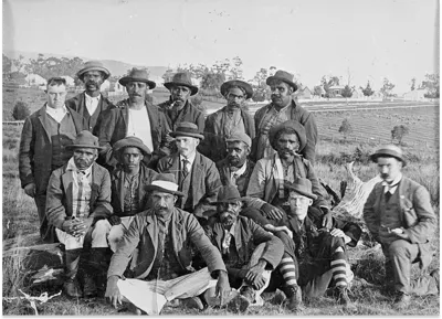 Historic black-and-white group photograph showing people seated and standing outdoors at Coranderrk, Victoria, in 1893.