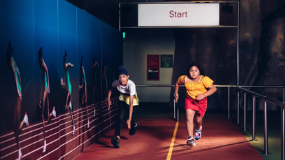Students participate in a race against Cathy Freeman in the Sportsworks exhibition.