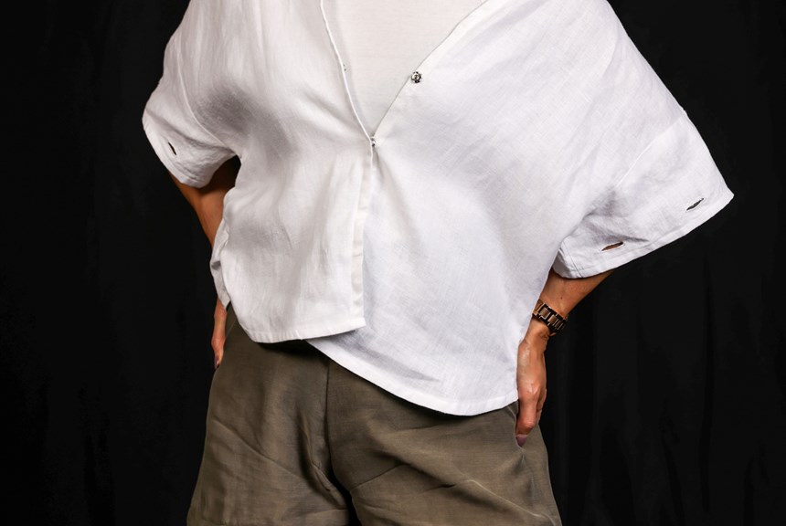 Person wearing a short sleeved white shirt and khaki bottoms. There are a number of buttonholes along the sleeves of the shirt.