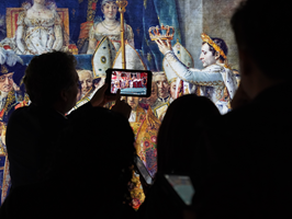 Silhouetted person holds electronic tablet in front of an image of an interior of Notre Dame cathedral