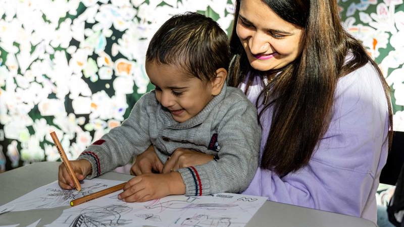 Child and parent decorating their Our Wondrous Country drawing at Melbourne Museum