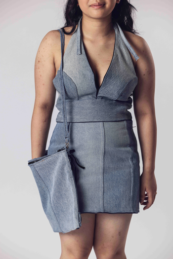Person wears a sleeveless denim halter top and matching skirt with a side bag made of the same fabric.