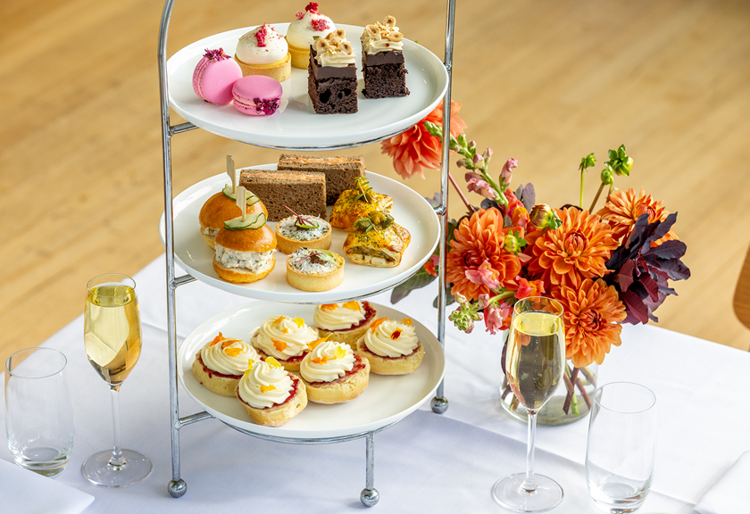 Dainty high tea food on a tiered silver tray.