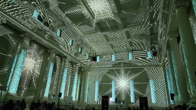 People watching a lightshow projected on the walls of the Long Room at the Immigration Museum.
