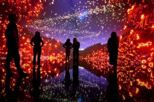 The silhouette of five people against a colourful ceiling height digital display 