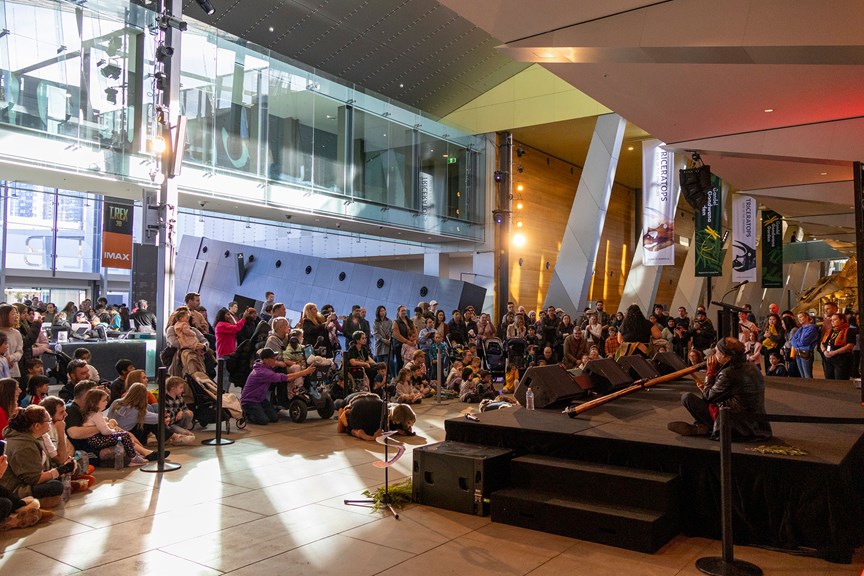 Amos Roach and the Murrundaya Yepenga Dance Troupe performing to a large audience during the Family Day event for NAIDOC Week held at Melbourne Museum. 