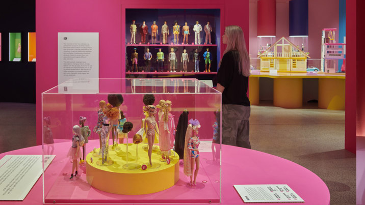 A display of barbie is in the foreground and a display of kens is in the background.