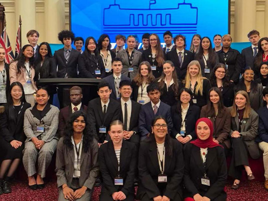 Approximately 30 Youth Parliament 2025 Participants kneel and stand for a group photo.