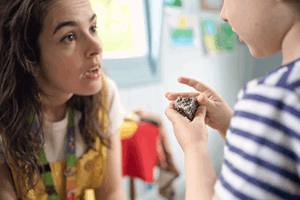 Kindergarten child engaging in hands-on learning by touching a real meteorite during Museum Victoria's Rockets and Robots kindergarten incursion program.