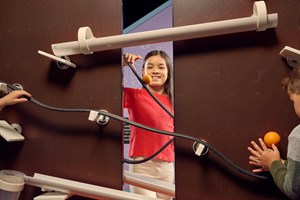 Children having fun designing their own roller-coaster for balls using different parts on a peg-wall.