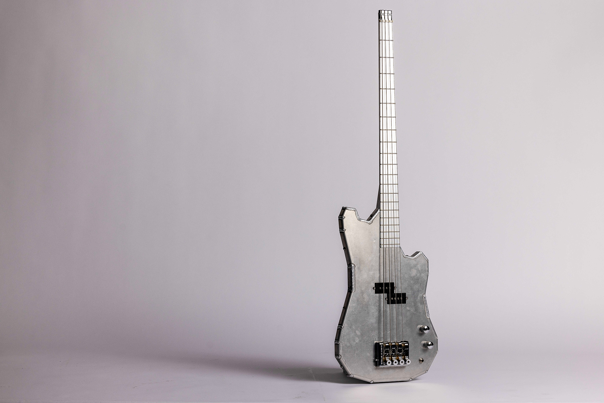 Aluminium-bodied bass guitar with angular shape, five strings, and black pickups.