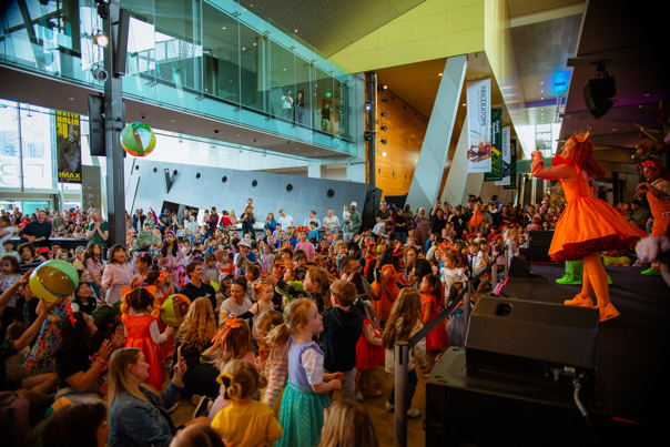Emma Memma performing on stage in Melbourne Museum foyer.