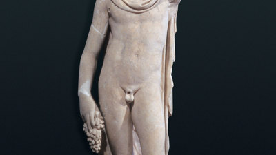 Marble statue of Bacchus holding grapes next to a dog.