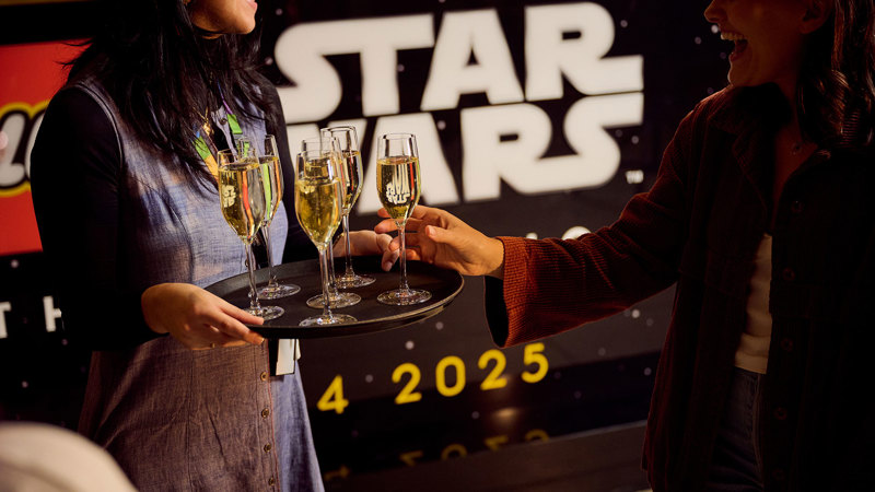 Museum guests are served glasses of champagne while attending LEGO Star Wars Exhibition during Adult Museum Sleepovers at Melbourne Museum.