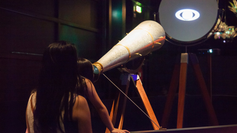 Mother and child looking through a telescope. 