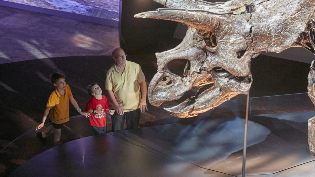 A man and his children looking at Horridus the Triceratops.