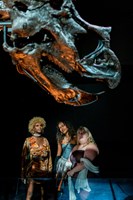 Three women stare at the massive head of a dinosaur in the Dinosaur Walk Exhibition.