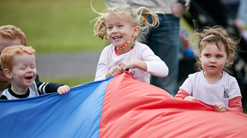 Children holding a colourful parachute at Little Kids' Day In at Scienceworks.